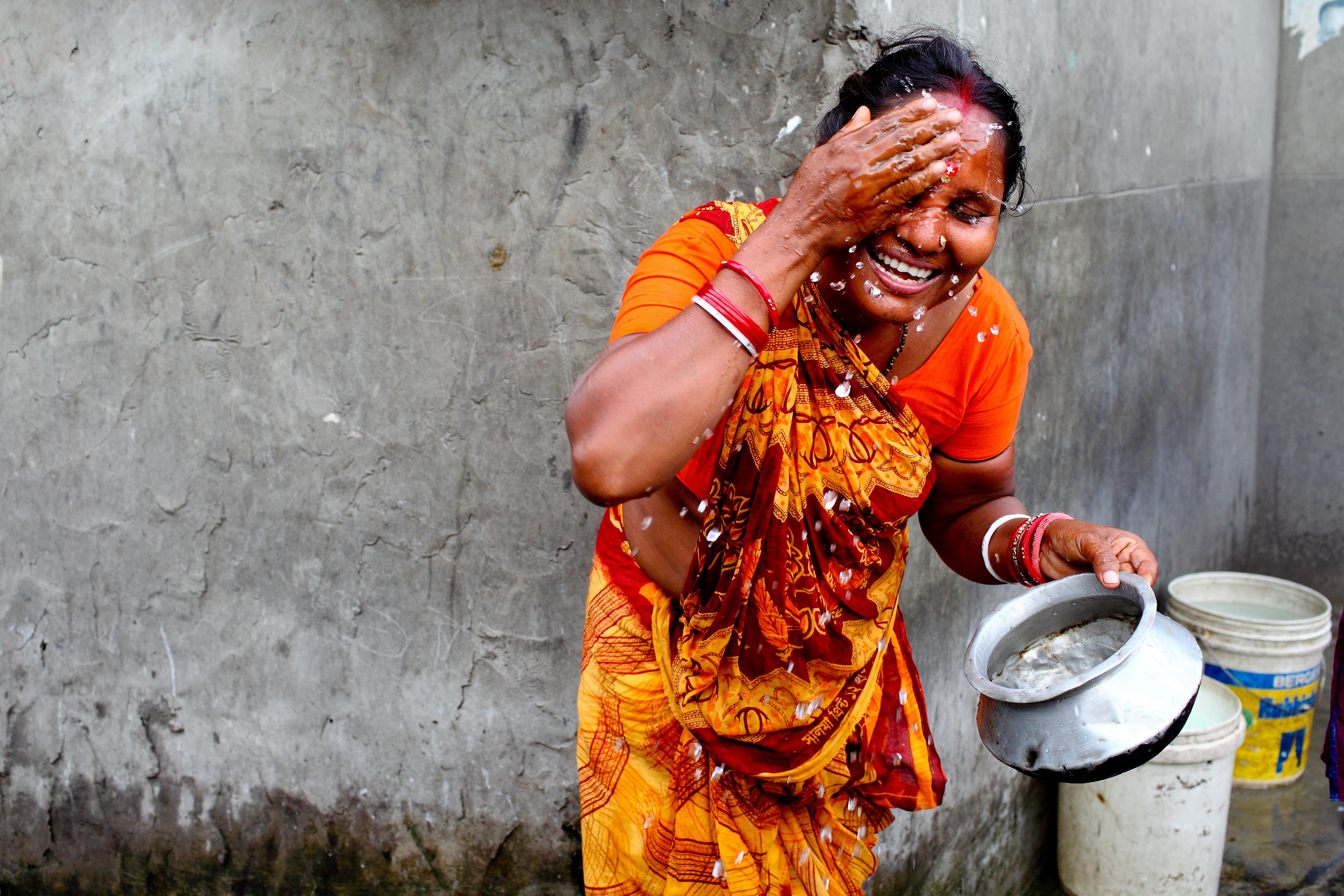 A woman is washing face early in the morning in TT Para Slum, Komlapur.